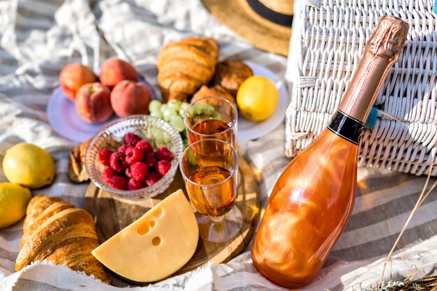 Chiuda sull'immagine di cibo gustoso in picnic, colori solari, pane di frutta di formaggio e champagne, colazione ostinata all'aperto.