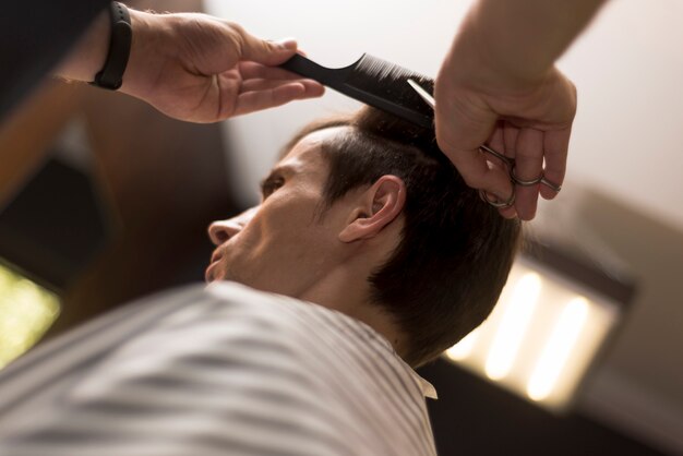 Chiuda sull&#39;uomo basso di vista che ottiene un taglio di capelli