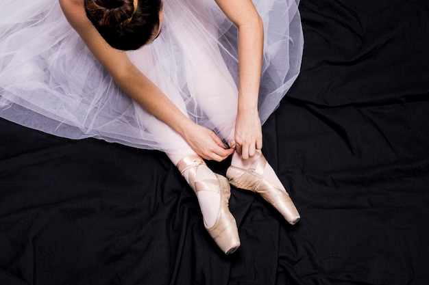 Chiuda sulla ballerina che lega le sue scarpe da punta