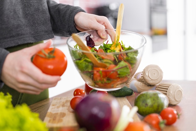 Chiuda sulla ciotola della holding della mano con insalata