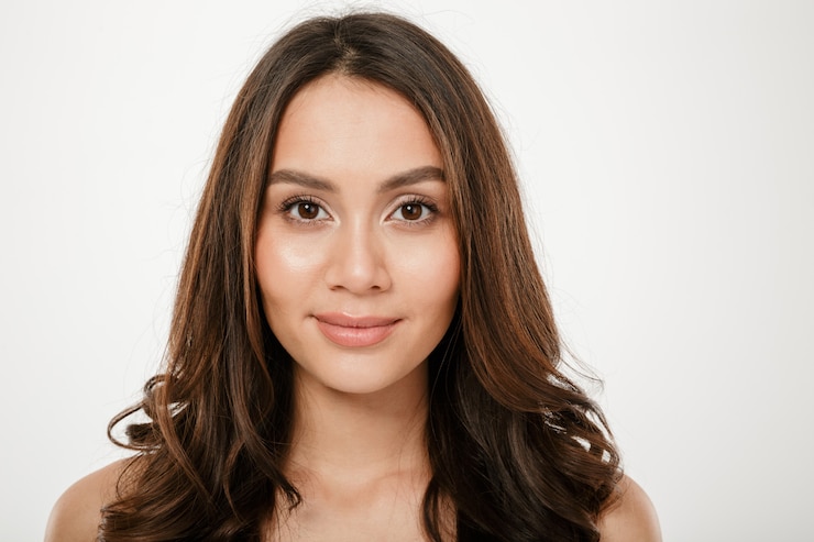 Foto gratuito chiuda sulla donna castana che esamina la macchina fotografica sopra grey