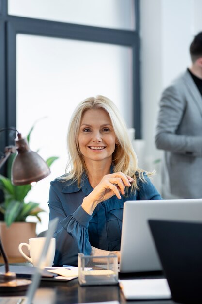 Chiuda sulla donna sorridente alla scrivania