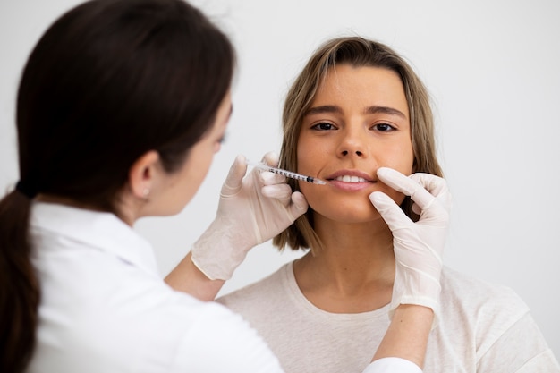 Chiuda sulla donna sorridente che ottiene riempitore del labbro