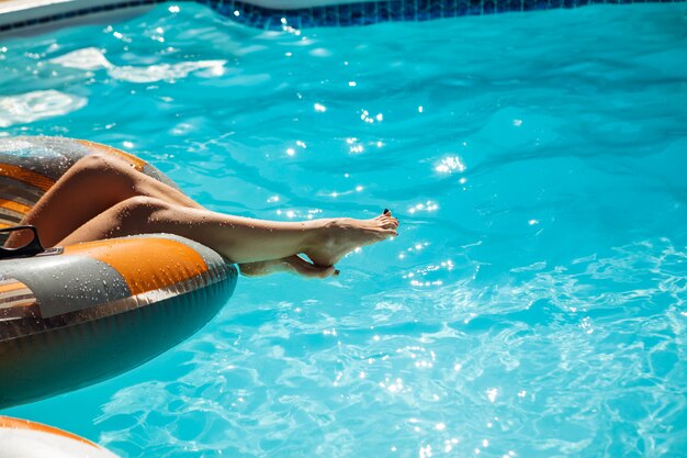 Chiuda sulla foto delle gambe della donna nella piscina