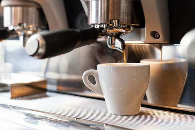 Chiuda sulla macchina che versa il caffè in tazza