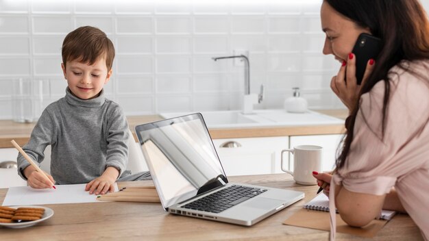 Chiuda sulla madre che lavora con il computer portatile