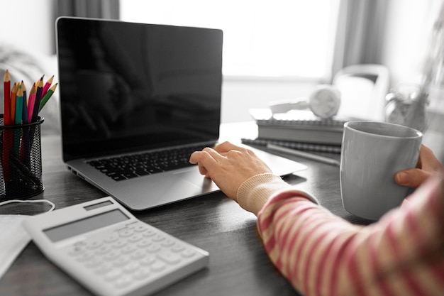 Chiuda sulla mano che lavora con il computer portatile