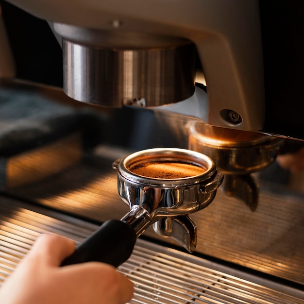 Chiuda sulla mano che prepara il caffè