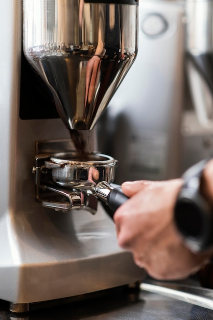 Chiuda sulla mano che prepara il caffè