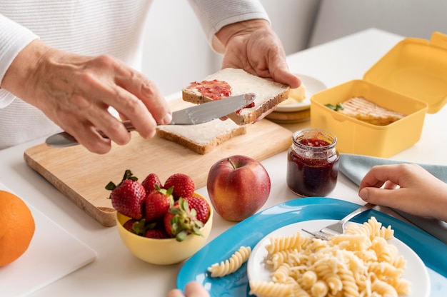 Chiuda sulla marmellata di diffusione della mano sul pane