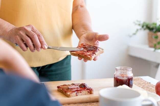 Chiuda sulla marmellata di diffusione della mano sul pane