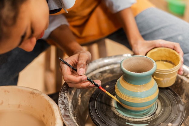 Chiuda sulla pentola di creta della pittura della donna