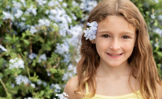 Chiuda sulla ragazza che posa con il fiore nei capelli