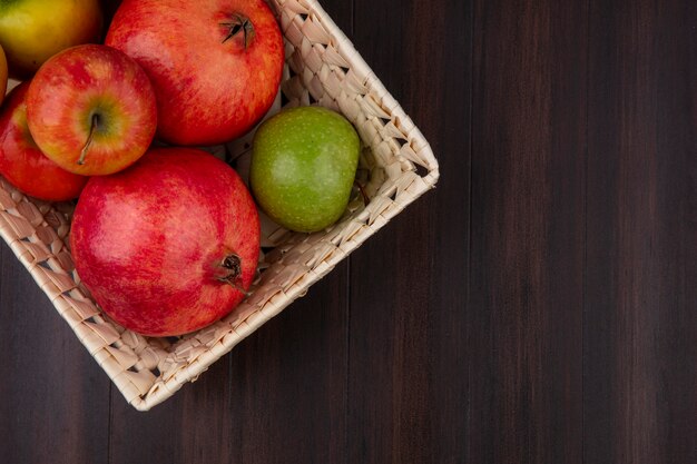 Chiuda sulla vista dei frutti come merce nel carrello della mela e del melograno su superficie di legno