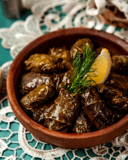 Chiuda sulla vista del dolma tradizionale in foglie di vite in una ciotola dell'argilla