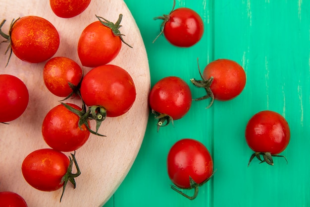 Chiuda sulla vista del modello dei pomodori sul tagliere su superficie verde