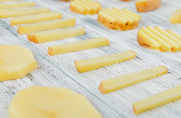 Chiuda sulla vista del modello delle patate affettate su fondo di legno