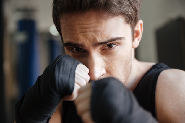 Chiuda sulla vista del pugile serio che fa l'esercizio in palestra