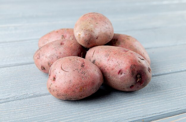 Chiuda sulla vista delle patate su fondo di legno con lo spazio 2 della copia