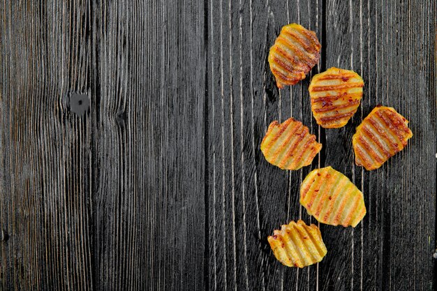 Chiuda sulla vista delle patatine fritte dalla destra e del fondo di legno con lo spazio della copia