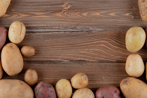 Chiuda sulla vista di intere patate su fondo di legno con lo spazio della copia