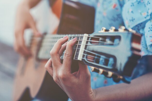 Chiuda sulle immagini delle mani della donna che giocano la chitarra acustica