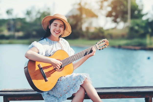 Chiuda sulle immagini delle mani della donna che giocano la chitarra acustica