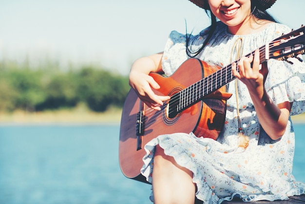 Chiuda sulle immagini delle mani della donna che giocano la chitarra acustica