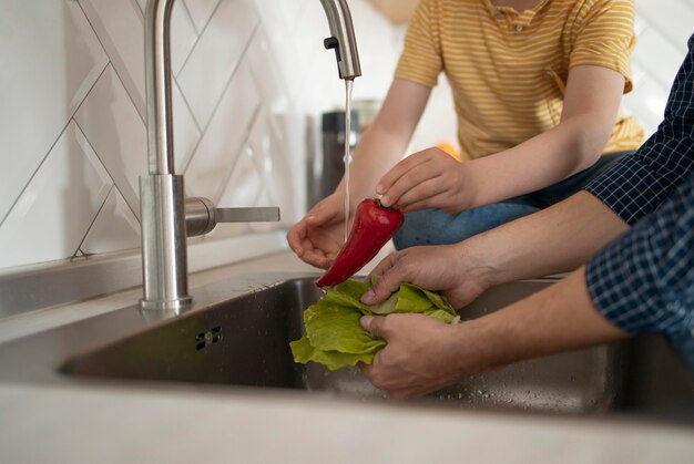 Chiuda sulle mani che lavano le verdure