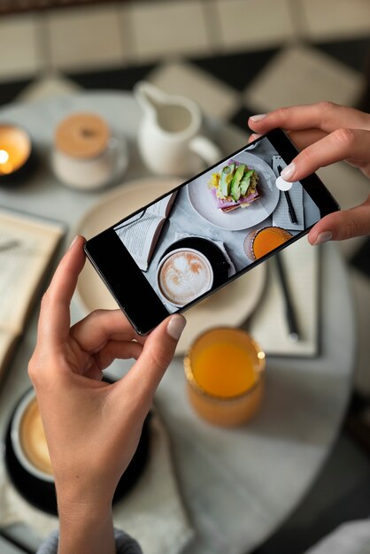 Chiuda sulle mani che prendono la foto del cibo