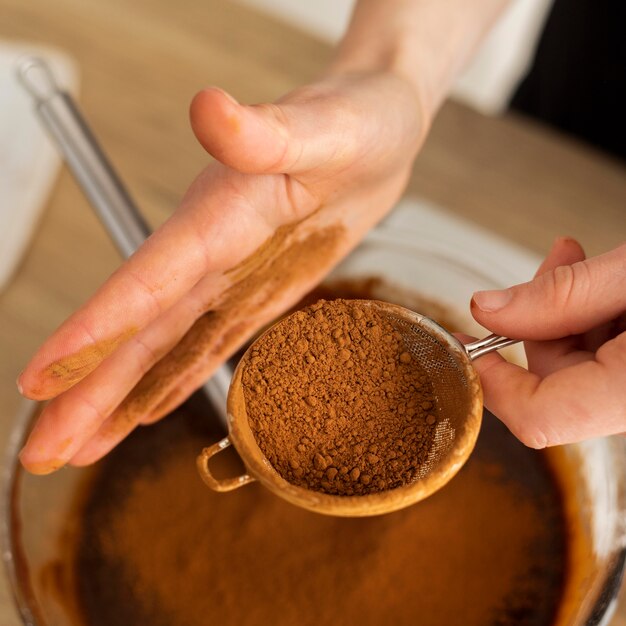 Chiuda sulle mani che preparano la miscela del cioccolato