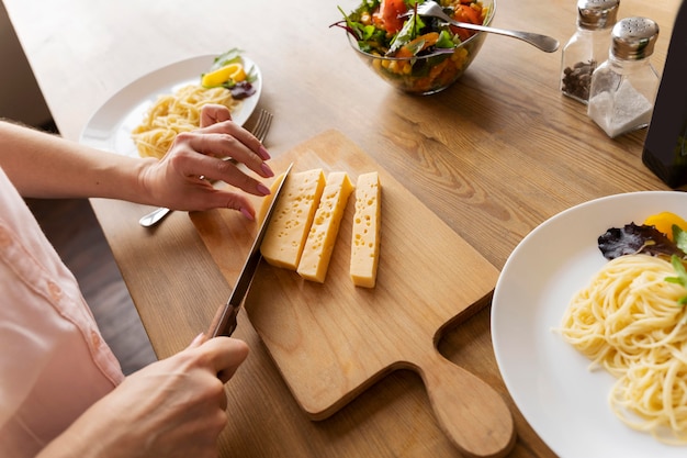 Chiuda sulle mani che tagliano il formaggio