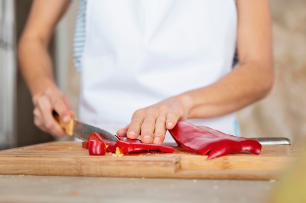 Chiuda sulle mani che tagliano il peperone dolce