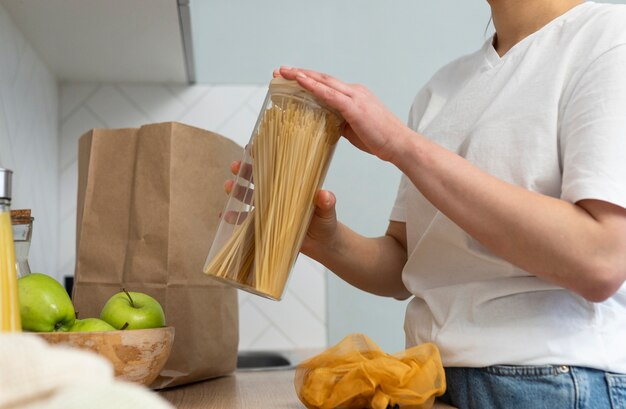 Chiuda sulle mani che tengono il contenitore della pasta