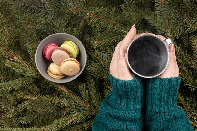 Chiuda sulle mani che tengono la tazza con la bevanda calda