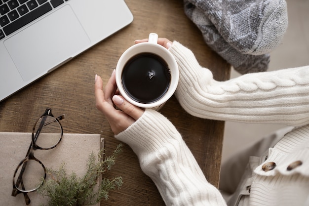 Chiuda sulle mani che tengono la tazza di caffè