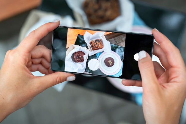 Chiuda sulle mani che tengono le foto del dessert