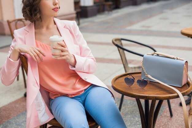 Chiudere i dettagli degli accessori della donna alla moda che si siede nel caffè bevendo caffè, occhiali da sole, borsetta, tendenza moda primavera estate, stile elegante