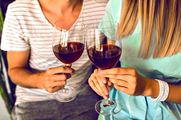 Chiudere i dettagli della serata romantica di belle coppie che bevono vino rosso e godersi il tempo insieme, interni moderni e abiti eleganti alla moda.