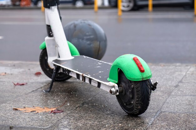 Chiudere il colpo di uno scooter elettrico parcheggiato vicino alla strada con auto in movimento, tempo umido e nuvoloso a Bucarest, Romania