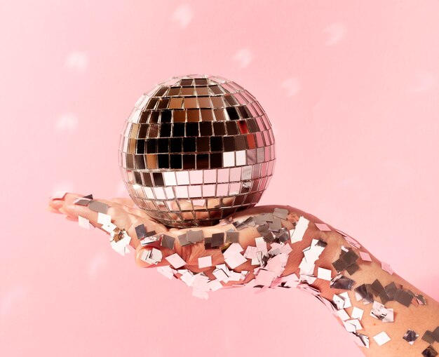 Chiudere la mano con il globo della discoteca e glitter