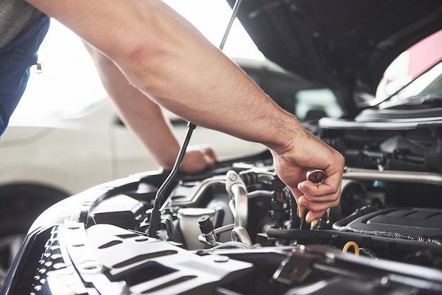 Chiudere le mani di un meccanico irriconoscibile che fa il servizio e la manutenzione dell'auto.