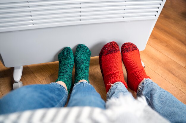 Chiudere le persone con le gambe vicino al riscaldatore a casa