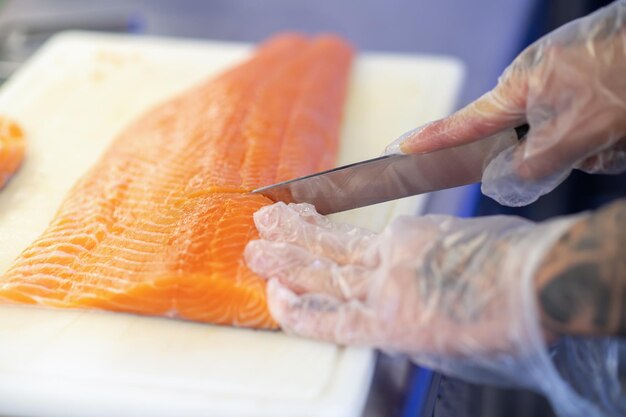 Chiusura delle mani dell'uomo che tagliano il pesce su un tagliere