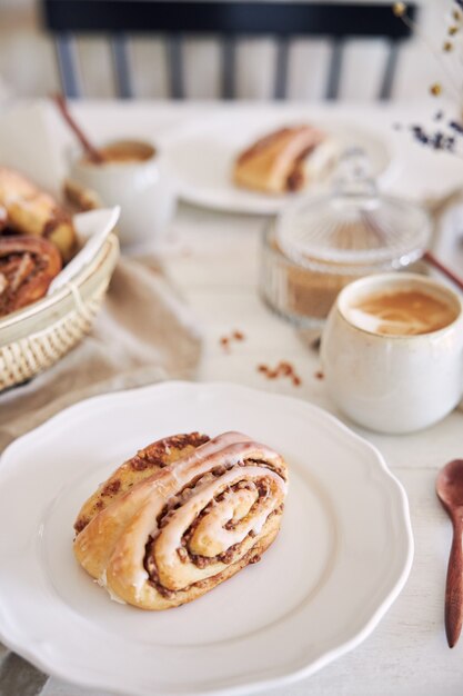 Chiusura verticale di deliziose lumache di noci con cappuccino di caffè sul tavolo di legno bianco