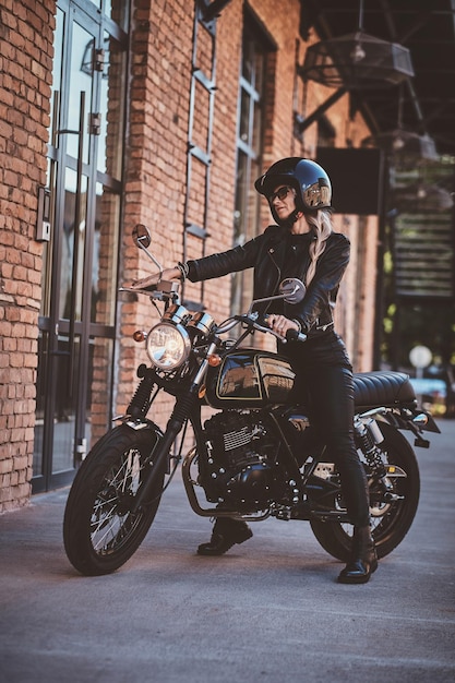 Ci sono donne mature sexy in occhiali da sole e casco protettivo nero sulla sua moto.