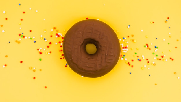 Ciambella al cioccolato con codette colorate su sfondo giallo