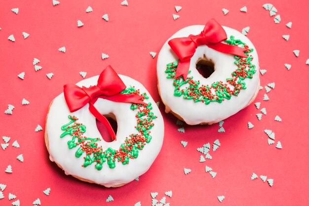 Ciambella deliziosa decorata per Natale su sfondo rosso con sprinkles