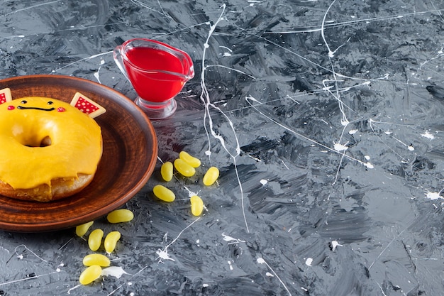 Ciambella smaltata gialla con caramelle di fagioli posta su un tavolo di marmo.