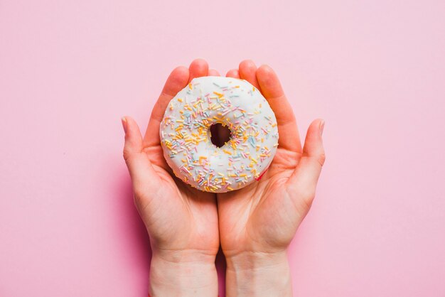 Ciambella umana della tenuta della mano su fondo rosa